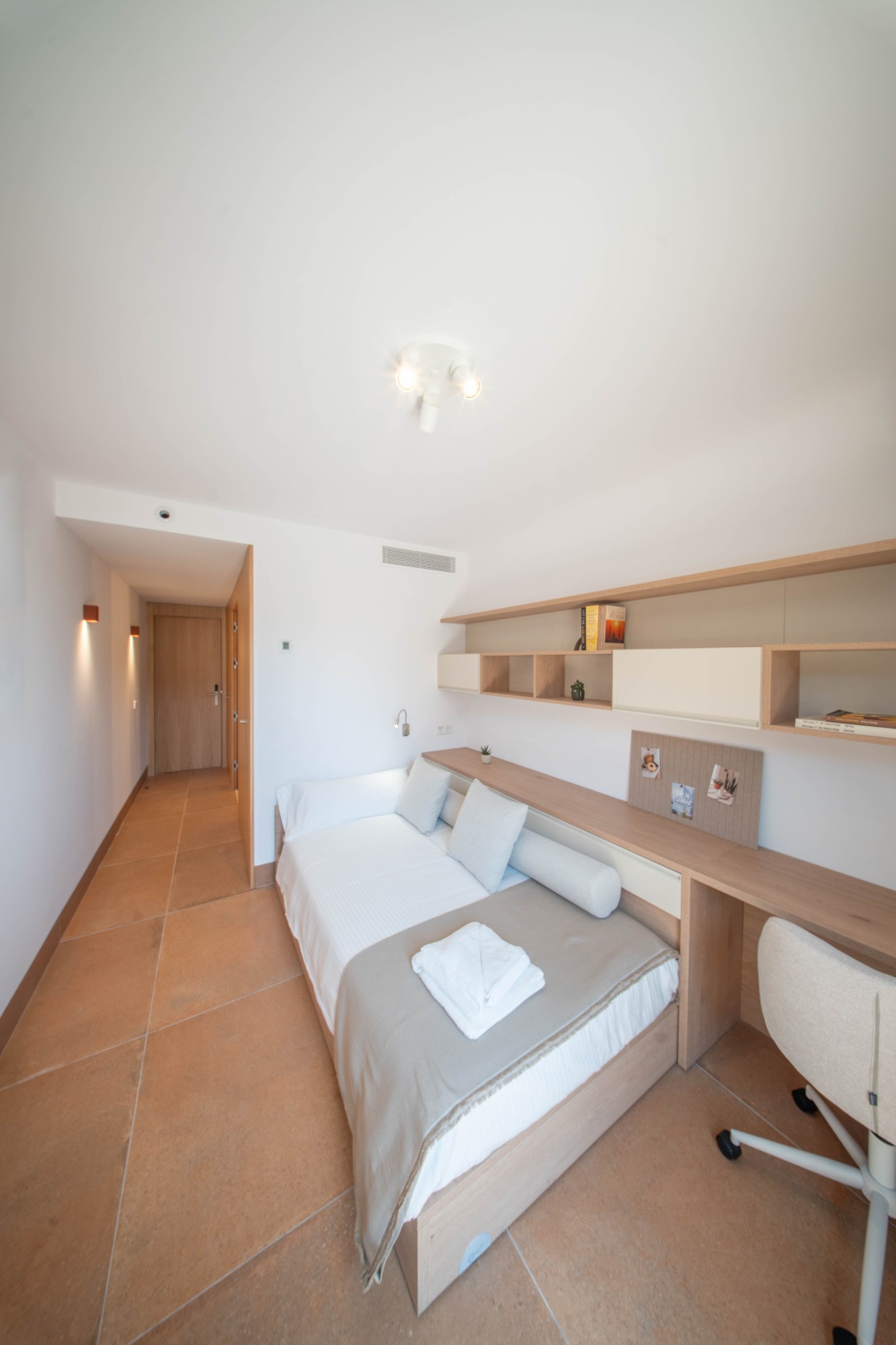 Single room with a bed, desk and shelving at the Jaume Ferran coliving in Palma
