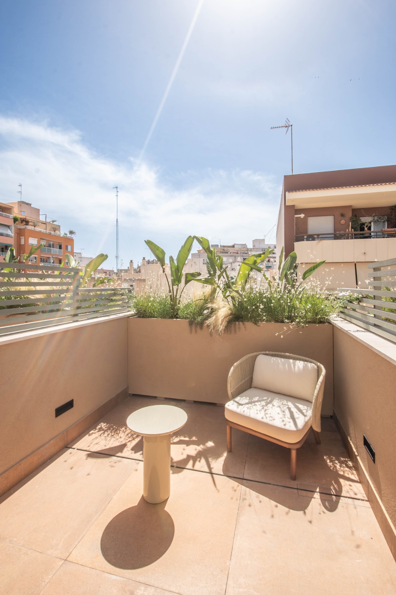 Private terrace of the penthouse at the Jaume Ferran coliving in Palma, with an armchair, side table and plants